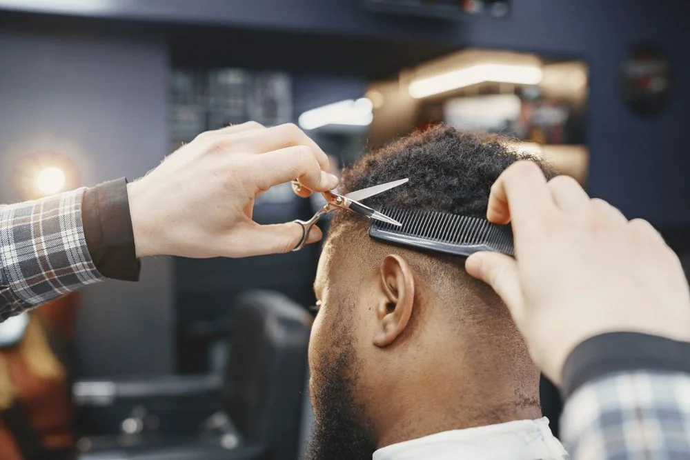 Scissors and comb refining the transition on the side of a short haircut