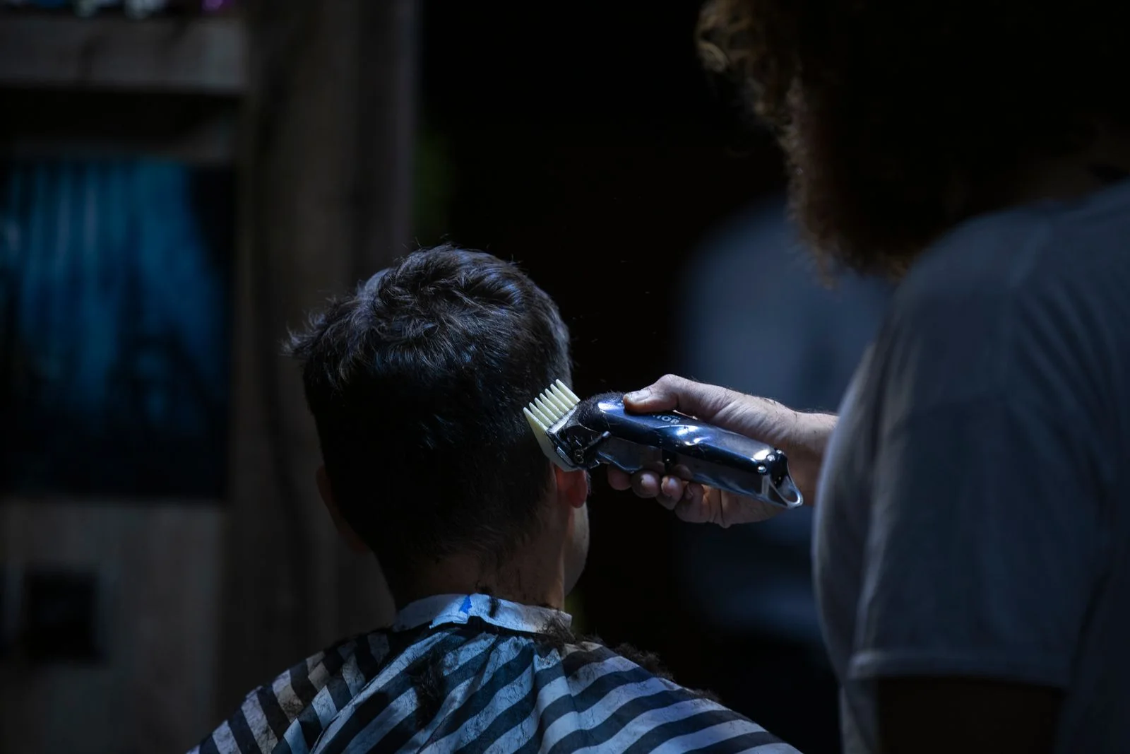 Barber using clippers to shape the back of a client's haircut