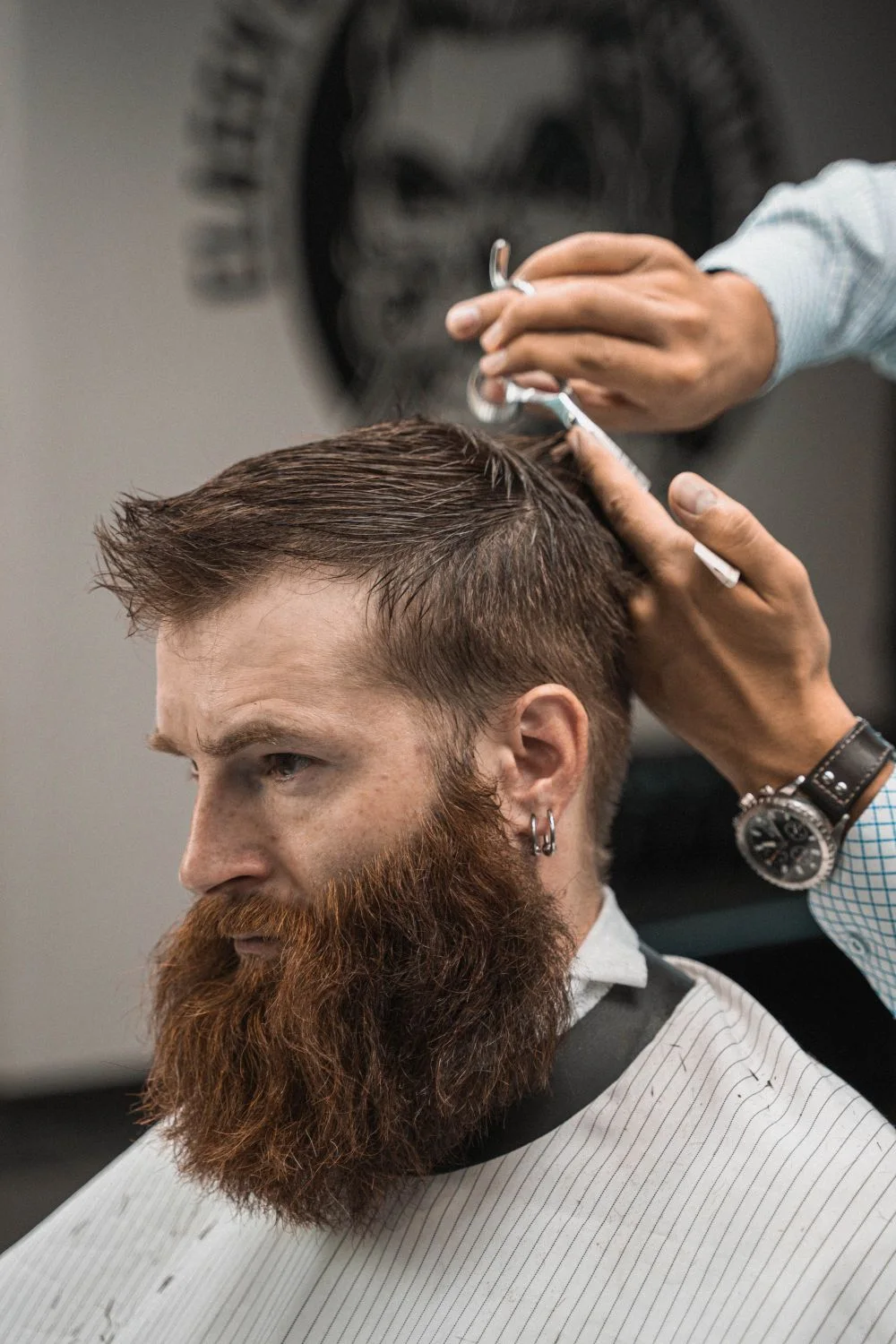 Scissors shaping a short haircut above a full beard